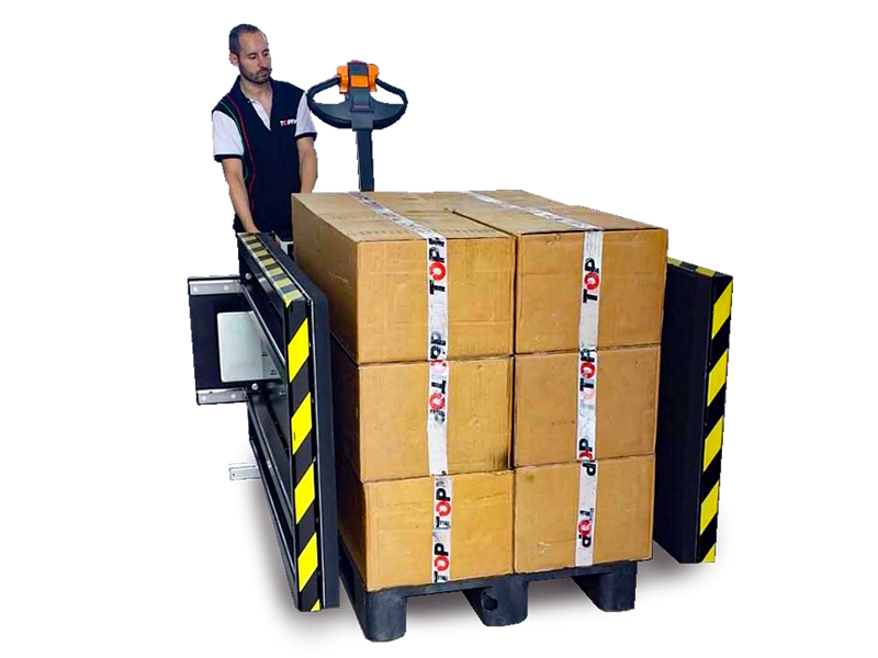黑色托盘交换机两侧伸出黄色夹具固定印有TOPPY标识的纸箱堆垛，操作员在控制面板前准备操作